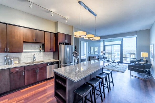 Nic on 5th Apartments in Minneapolis, Minnesota- Large common room with wooden cabinets, floors and granite countertops - NIC on 5th Apartments